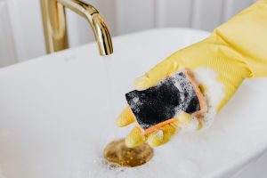 Person in glove using detergent and sponge while cleaning